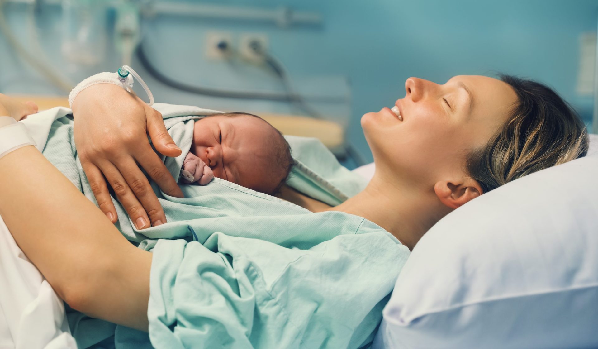 mother laying in a hospital bed holding her newborn baby
